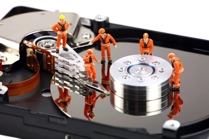 Small workman doing stuff on the surface of a hard disk drive