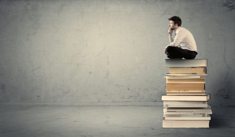 Man sitting on a pile of books