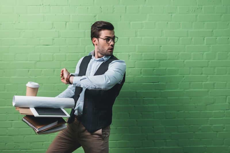 Man carrying a lot of stuff, looking at his watch and generally rushing