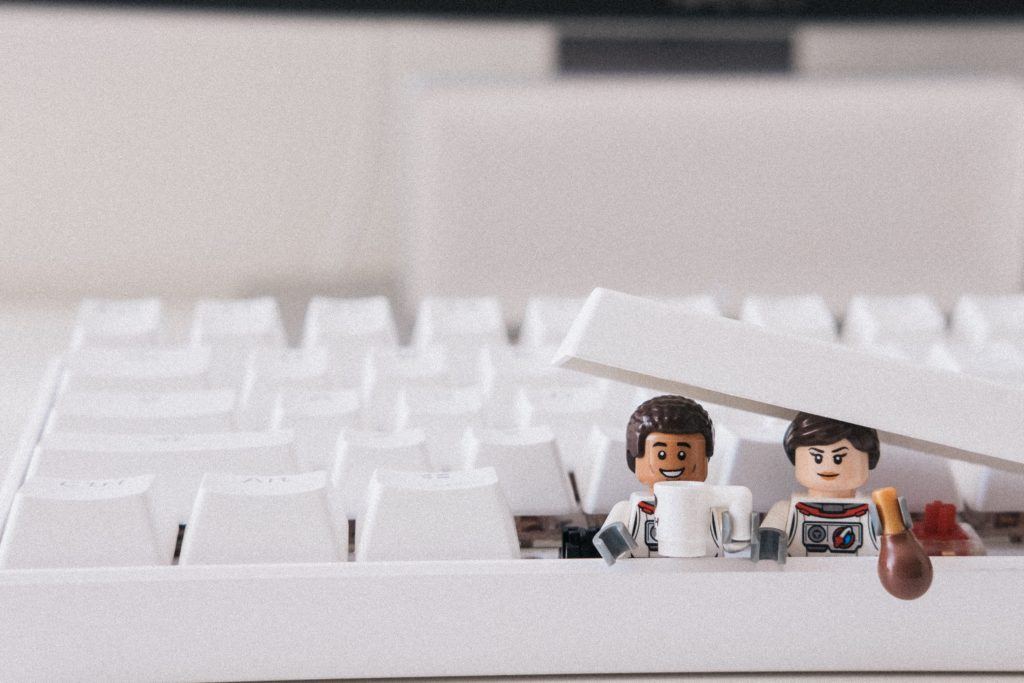 Two Lego minifigures hiding out in a keyboard